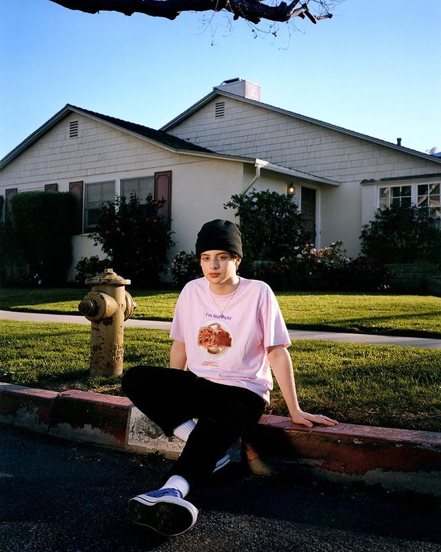 Thomas Barbusca in a light pink t-shirt, black pants, and cap.